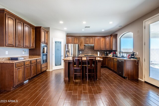 kitchen with stainless steel appliances, tasteful backsplash, sink, a kitchen breakfast bar, and a center island