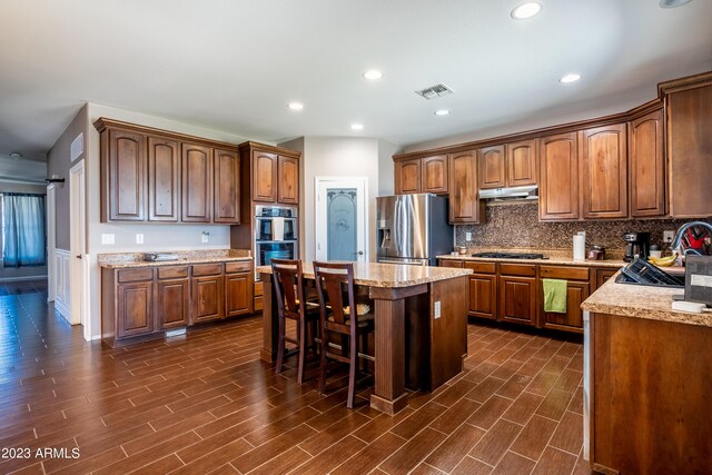 kitchen featuring a kitchen breakfast bar, a center island, sink, appliances with stainless steel finishes, and tasteful backsplash