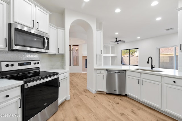 kitchen featuring stainless steel appliances, tasteful backsplash, ceiling fan with notable chandelier, white cabinets, and sink