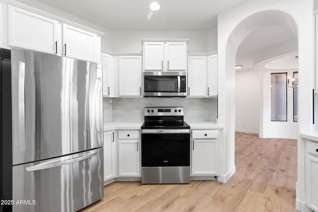 kitchen featuring decorative backsplash, appliances with stainless steel finishes, white cabinetry, and light hardwood / wood-style flooring