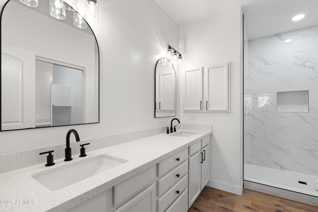 bathroom with hardwood / wood-style floors, tiled shower, and vanity