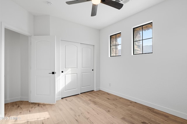 unfurnished bedroom featuring ceiling fan, a closet, and light wood-type flooring