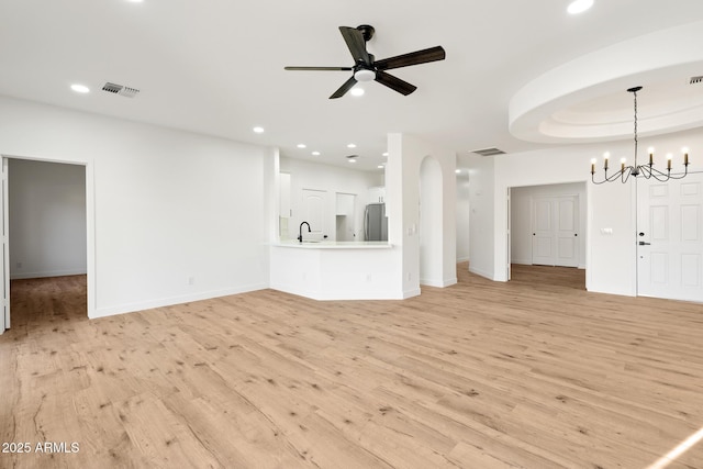 unfurnished living room featuring sink, ceiling fan with notable chandelier, and light hardwood / wood-style flooring