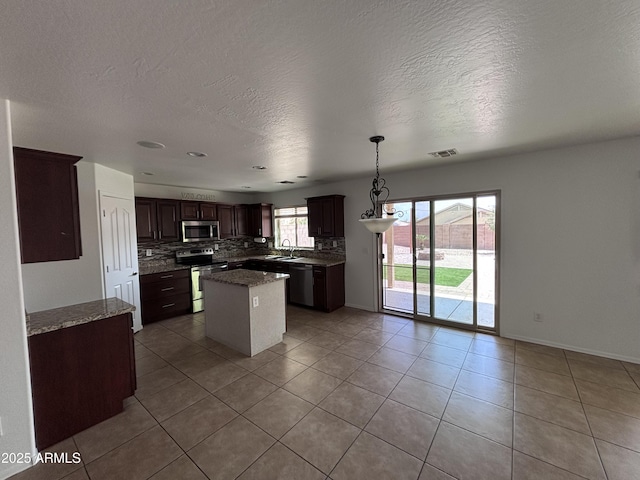 18629 W Fulton St, Goodyear, AZ 85338 - kitchen featuring appliances with stainless steel finishes, a kitchen island, backsplash, a textured ceiling, and light tile patterned floors