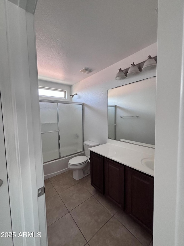 18629 W Fulton St, Goodyear, AZ 85338 - bathroom featuring vanity, tile patterned floors, shower / bath combination with glass door, toilet, and a textured ceiling