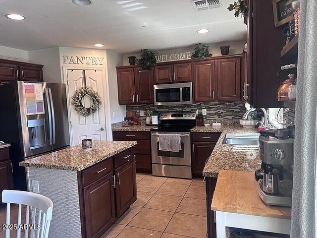 18629 W Fulton St, Goodyear, AZ 85338 - kitchen featuring stainless steel appliances, light tile patterned floors, dark brown cabinets, recessed lighting, and light stone countertops
