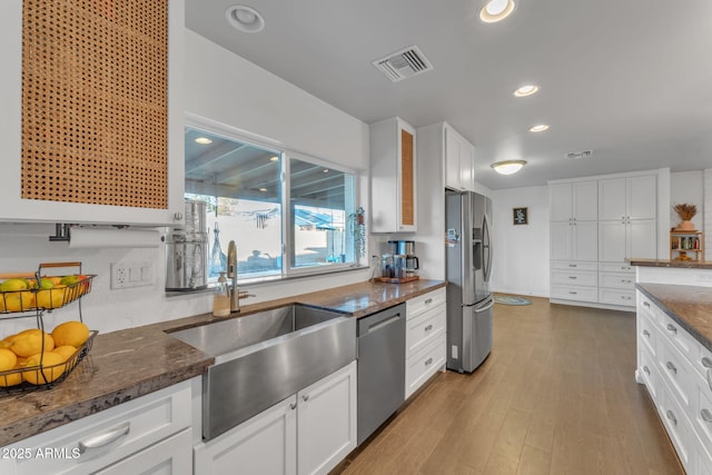 kitchen featuring appliances with stainless steel finishes, sink, dark stone countertops, and white cabinets