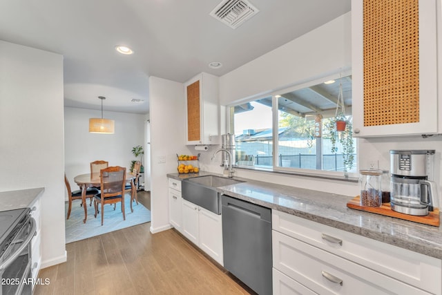 kitchen with sink, white cabinets, decorative light fixtures, stainless steel dishwasher, and light wood-type flooring