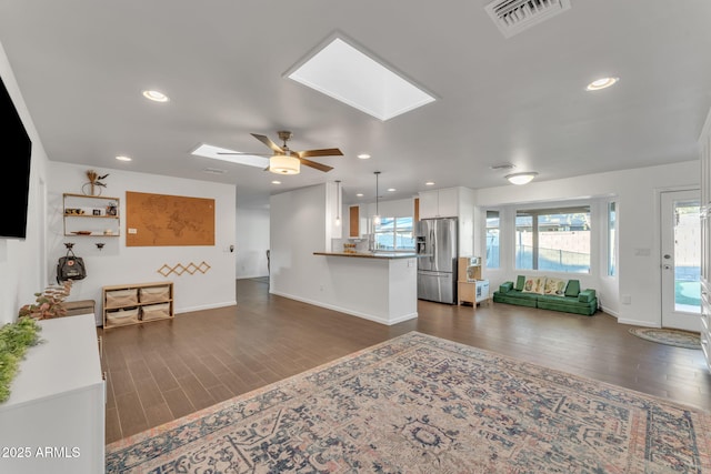 living room featuring ceiling fan, dark hardwood / wood-style flooring, and a skylight