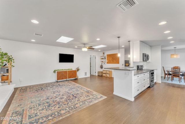 kitchen with white cabinetry, hanging light fixtures, a skylight, and appliances with stainless steel finishes