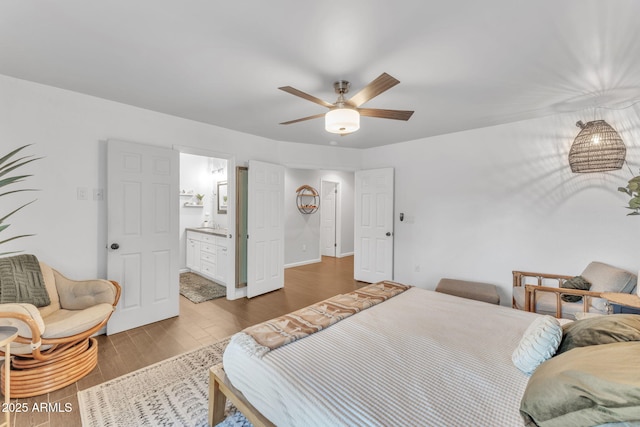 bedroom featuring ceiling fan, ensuite bath, and hardwood / wood-style flooring