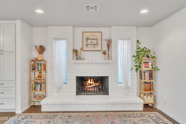 living room with a brick fireplace and dark hardwood / wood-style floors