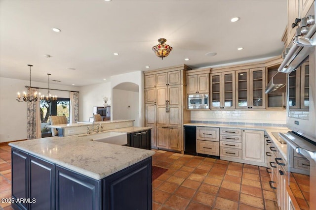 kitchen with a center island with sink, recessed lighting, a sink, appliances with stainless steel finishes, and backsplash