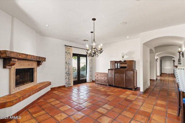 unfurnished dining area featuring visible vents, baseboards, arched walkways, french doors, and a glass covered fireplace