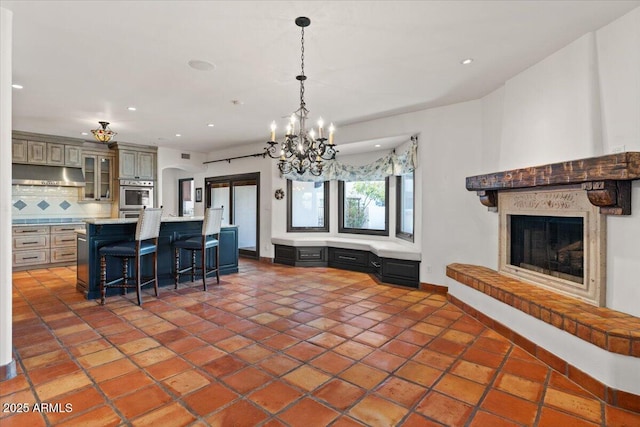 kitchen featuring tasteful backsplash, under cabinet range hood, light countertops, stainless steel oven, and arched walkways