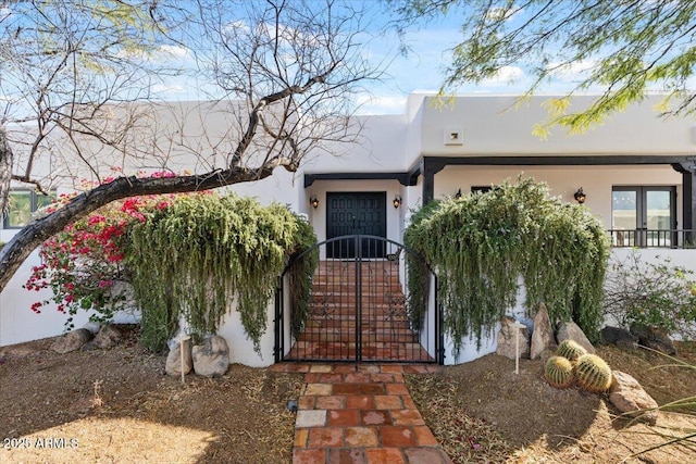 view of front facade featuring stucco siding and a gate