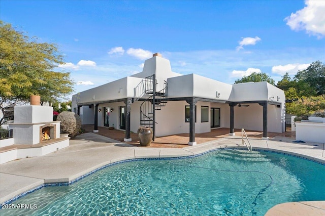 pool featuring stairway, a patio, and a lit fireplace