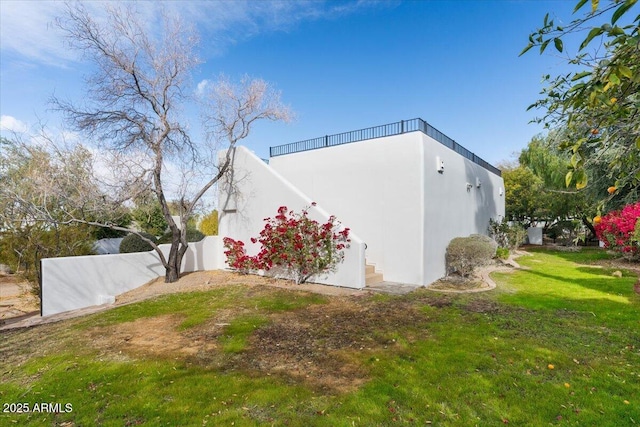 view of side of property with a yard, stucco siding, and fence