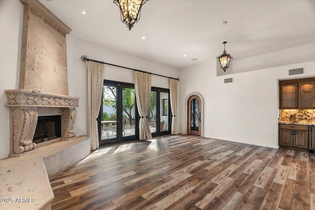 unfurnished living room with wood finished floors, visible vents, and a high end fireplace