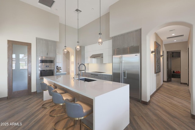 kitchen featuring sink, a kitchen bar, hanging light fixtures, a kitchen island with sink, and stainless steel appliances