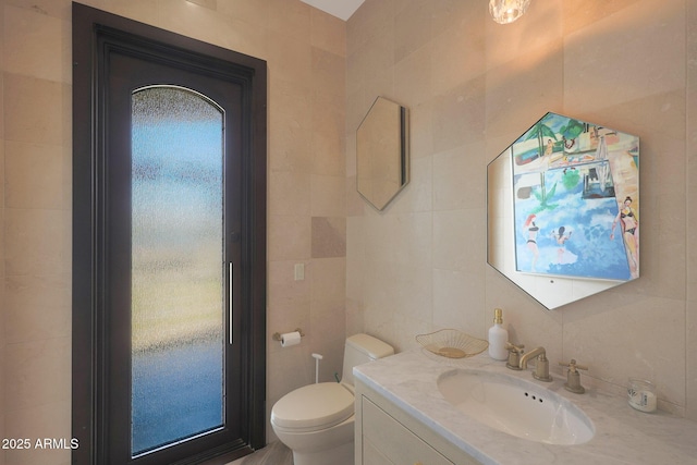 bathroom with vanity, tile walls, and toilet