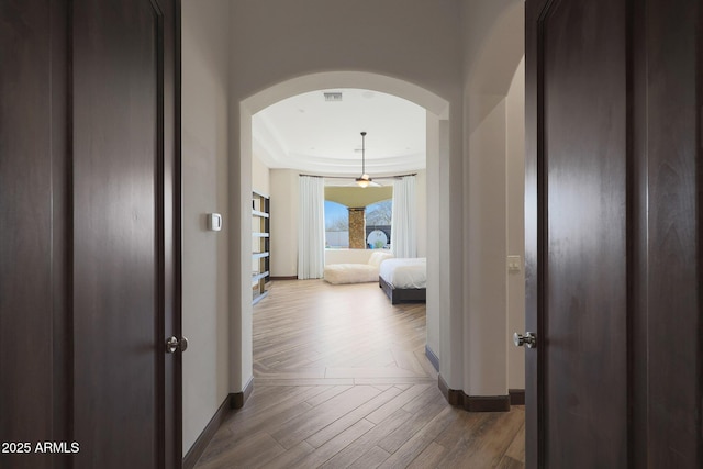 corridor featuring hardwood / wood-style flooring and a tray ceiling