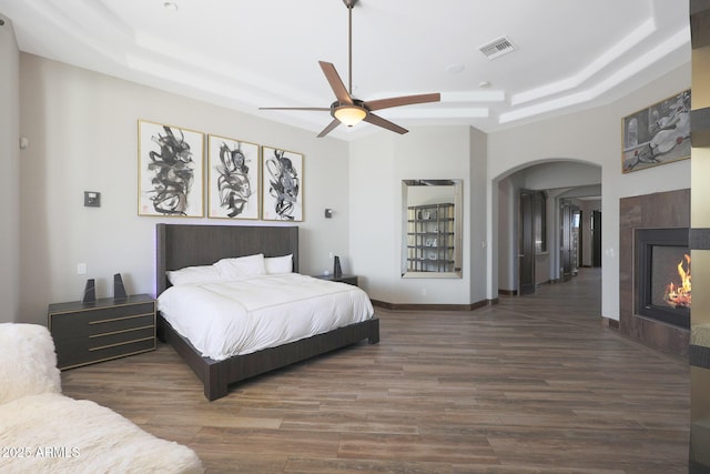 bedroom featuring dark hardwood / wood-style floors, ceiling fan, and a tray ceiling