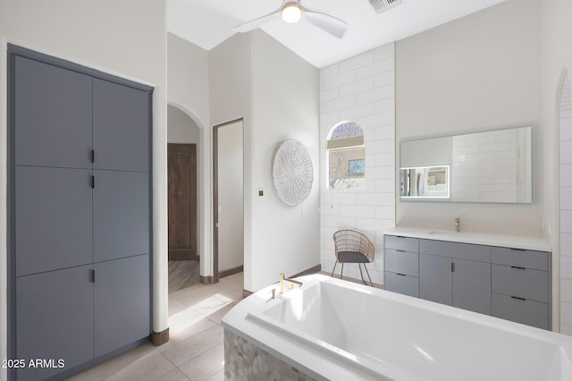 bathroom with vanity, a relaxing tiled tub, tile patterned floors, and ceiling fan