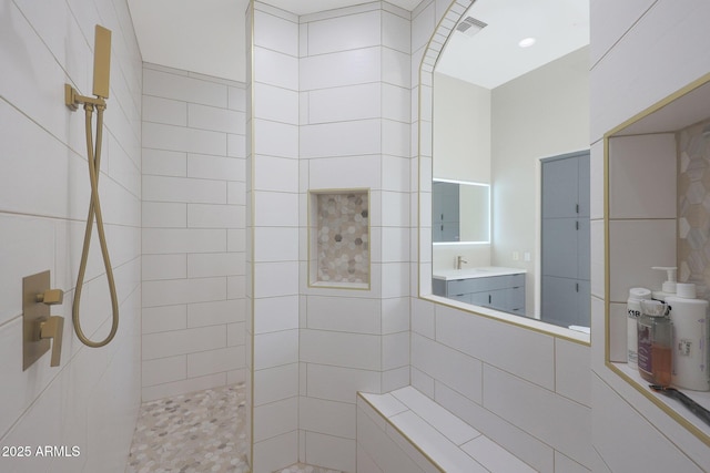 bathroom with vanity and a tile shower