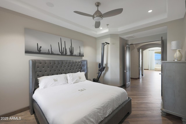 bedroom featuring dark hardwood / wood-style floors, a raised ceiling, and ceiling fan