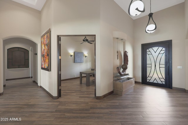 foyer with dark wood-type flooring and high vaulted ceiling