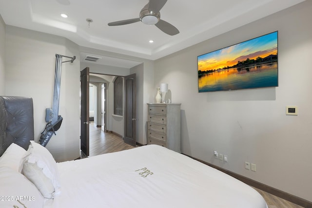 bedroom featuring hardwood / wood-style flooring, a raised ceiling, and ceiling fan