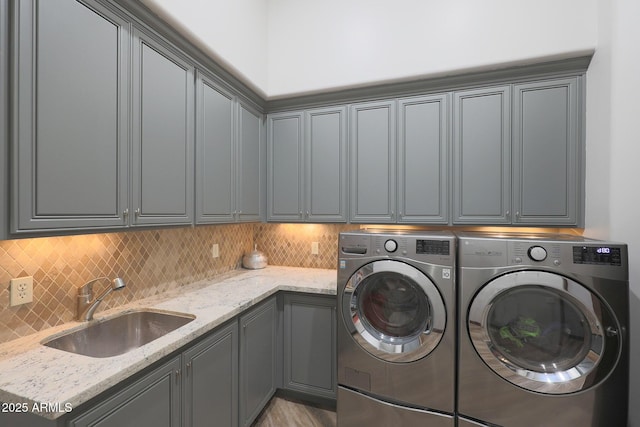 laundry area featuring separate washer and dryer, sink, and cabinets