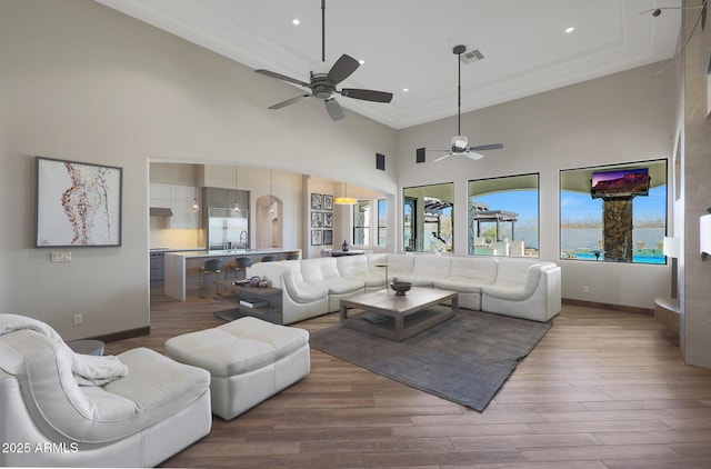 living room with sink, hardwood / wood-style flooring, ceiling fan, and a high ceiling