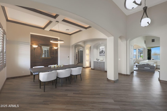 dining space with beamed ceiling, coffered ceiling, dark wood-type flooring, and a towering ceiling