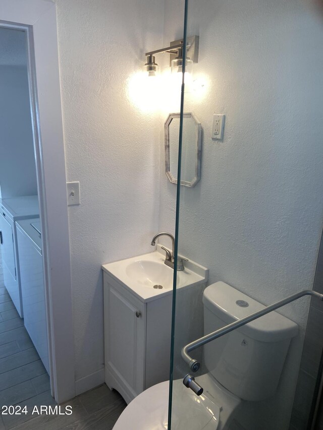 bathroom featuring vanity, washer and dryer, tile patterned flooring, and toilet