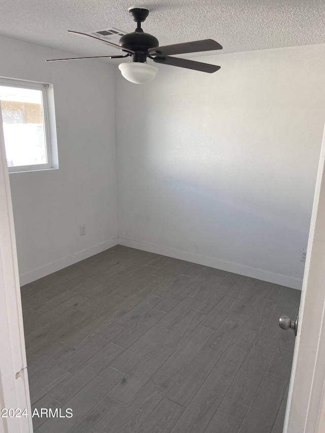 spare room with dark wood-style floors, ceiling fan, baseboards, and a textured ceiling