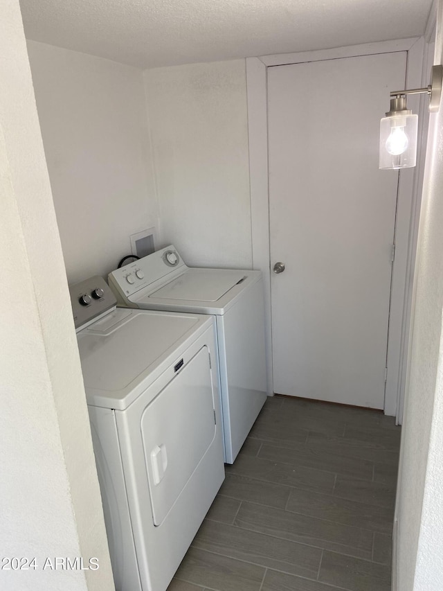 laundry room with a textured ceiling, laundry area, washing machine and clothes dryer, and wood tiled floor