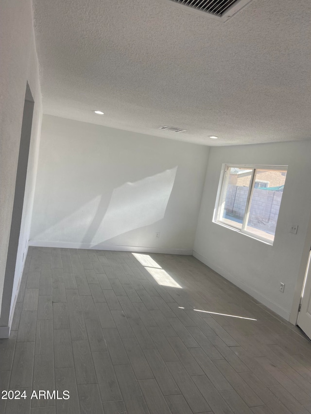 unfurnished room featuring dark wood-type flooring and a textured ceiling