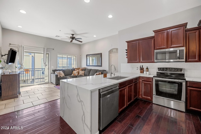 kitchen with sink, kitchen peninsula, appliances with stainless steel finishes, ceiling fan, and dark hardwood / wood-style floors