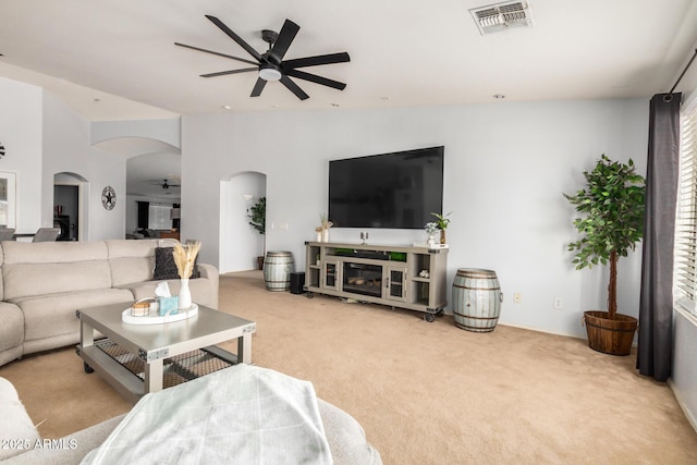 living room with a ceiling fan, carpet, arched walkways, and visible vents