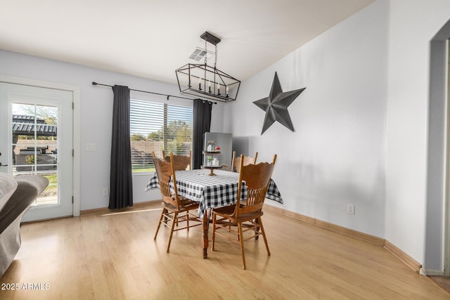 dining area with a notable chandelier, visible vents, light wood-type flooring, and baseboards