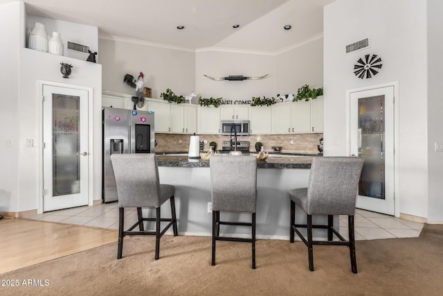 kitchen with visible vents, appliances with stainless steel finishes, white cabinetry, and a kitchen bar