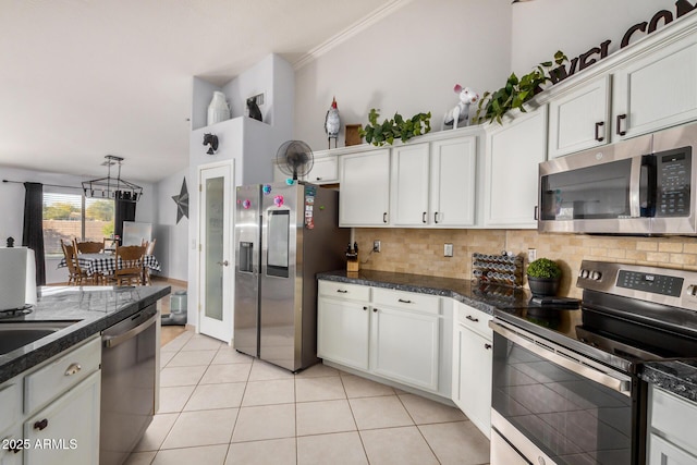 kitchen featuring dark countertops, light tile patterned floors, decorative backsplash, white cabinets, and stainless steel appliances