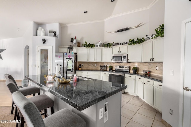 kitchen with dark countertops, a breakfast bar area, stainless steel appliances, and tasteful backsplash