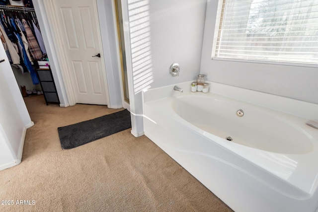 full bath with carpet floors, a bath, and a spacious closet