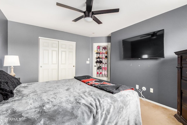 bedroom with a closet, light carpet, baseboards, and ceiling fan