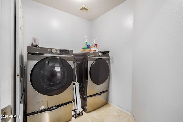 washroom with laundry area, washing machine and dryer, visible vents, and baseboards