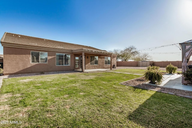 back of property with a yard, a patio area, a fenced backyard, and stucco siding