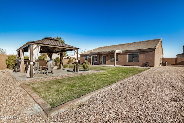 back of property with stucco siding, central AC, a gazebo, fence private yard, and a patio area